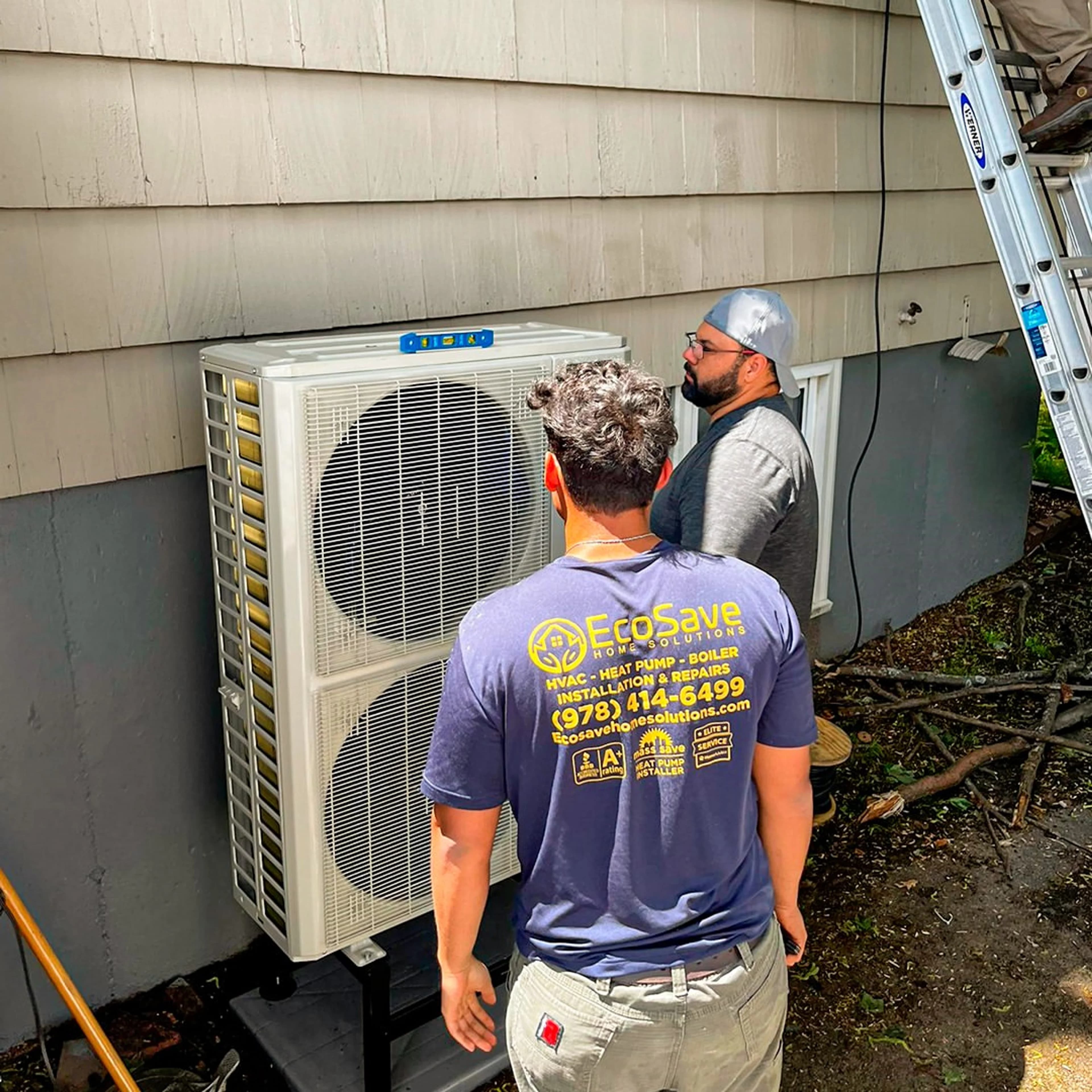 Two EcoSave home-services technicians installing an outdoor heat pump