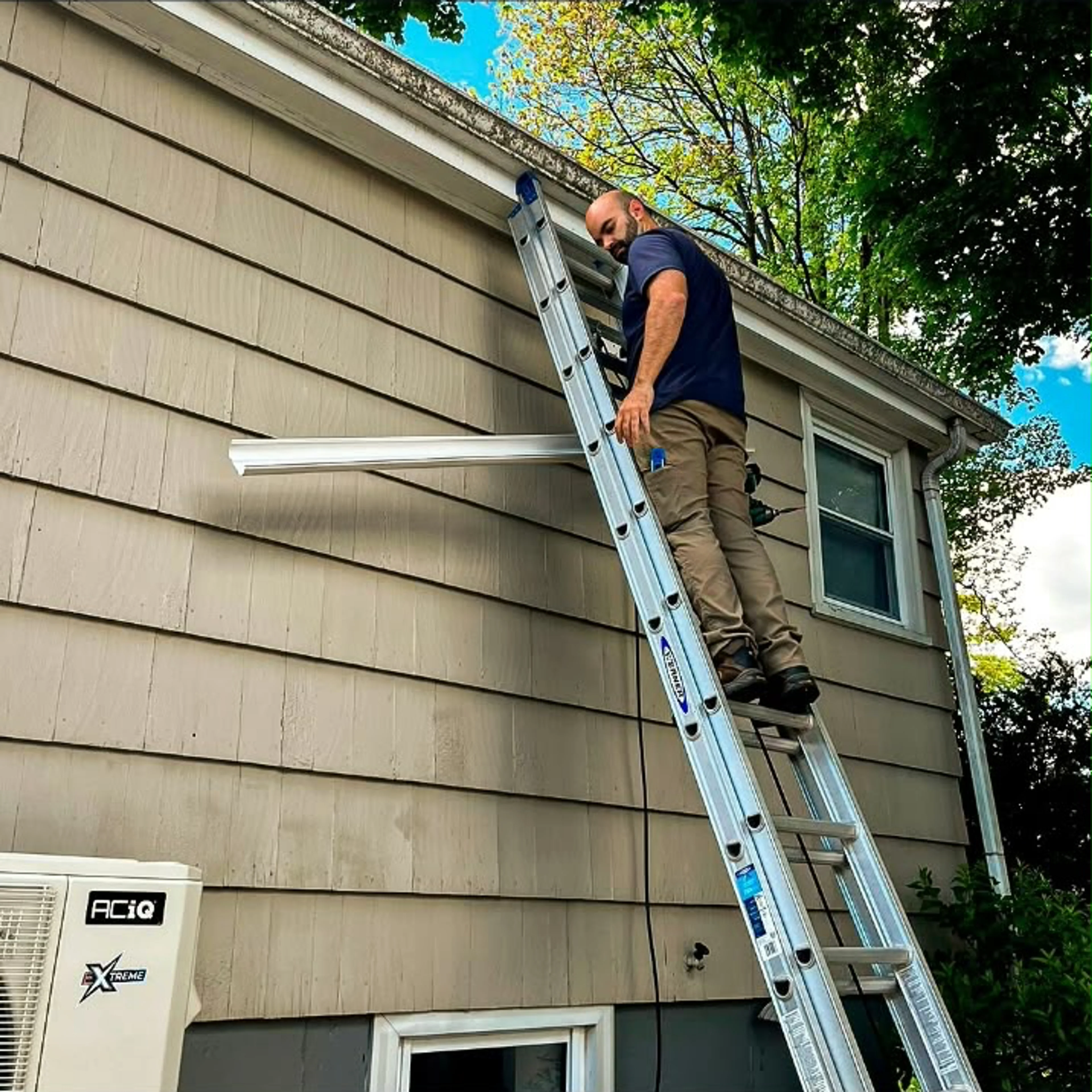 EcoSave home-services technician on a ladder beside a house