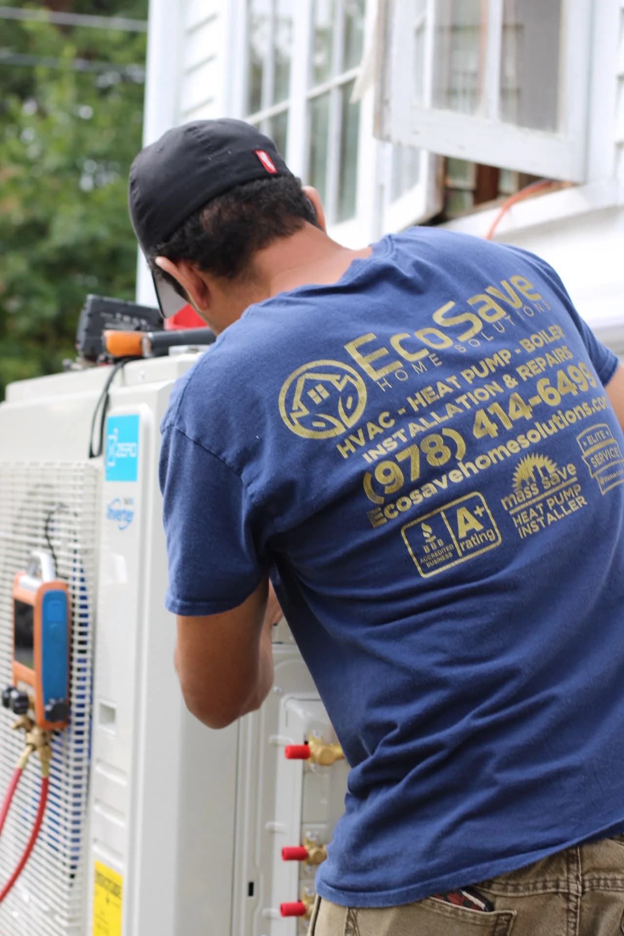An EcoSave technician in a branded shirt working on an outdoor heat pump